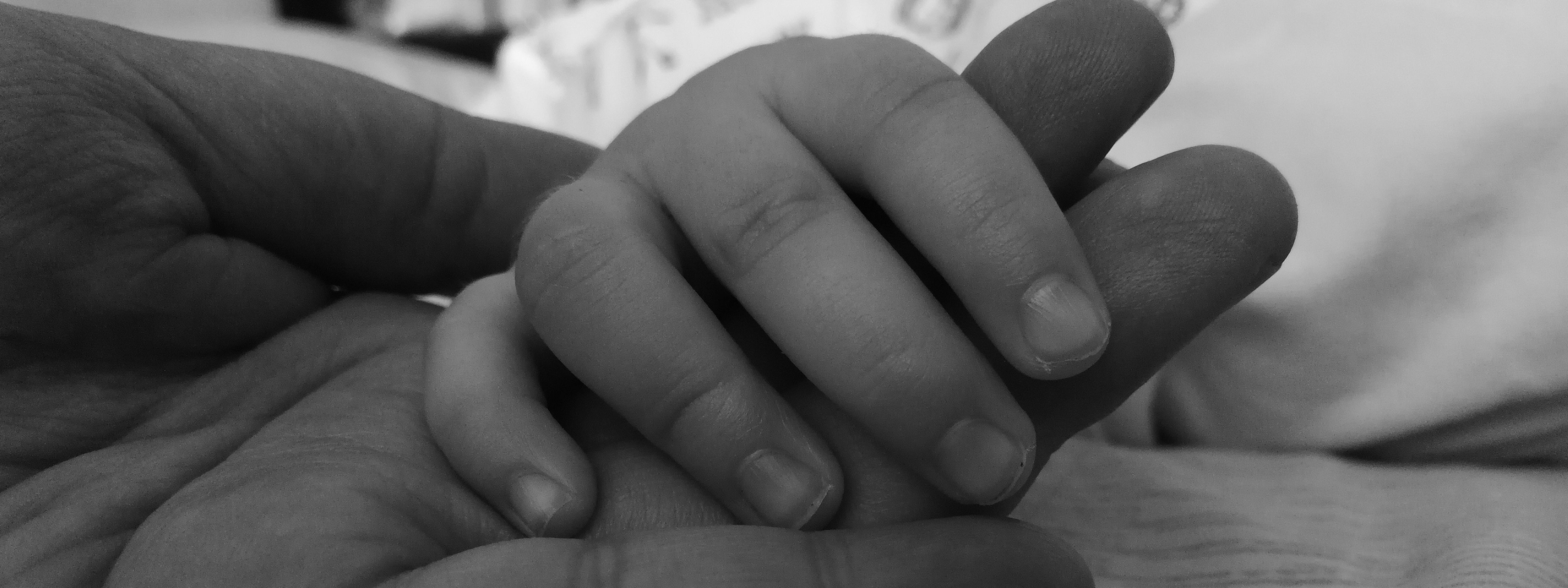 Un nourrisson tient la main de son père